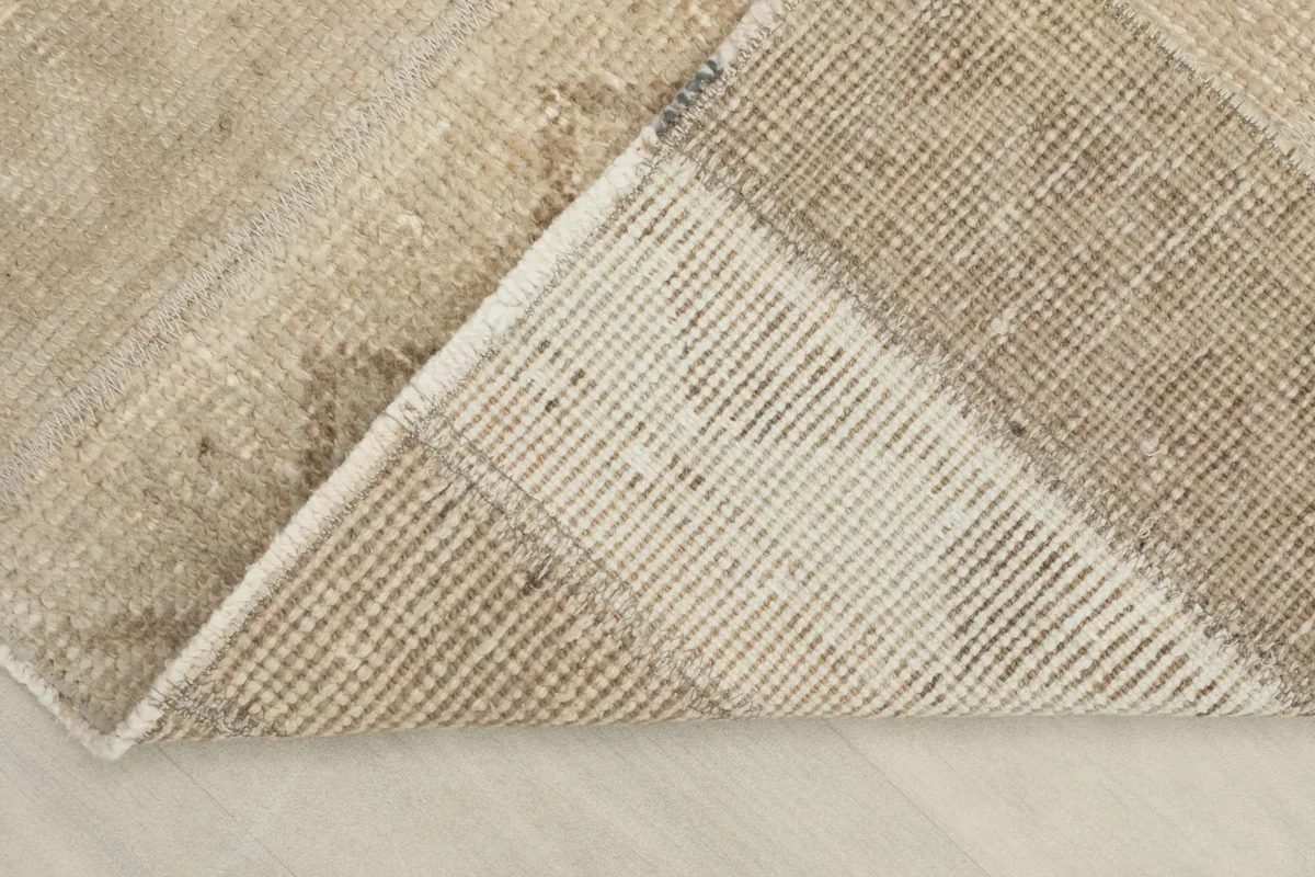 Corner of the rug folded back to show the cotton foundation and knotting
