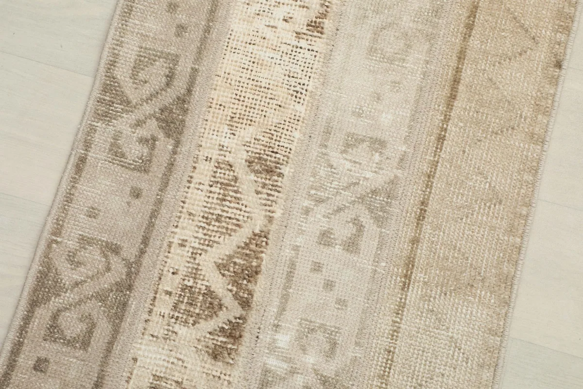 Close-up detail of the vintage beige runner rug's patchwork and geometric motifs.