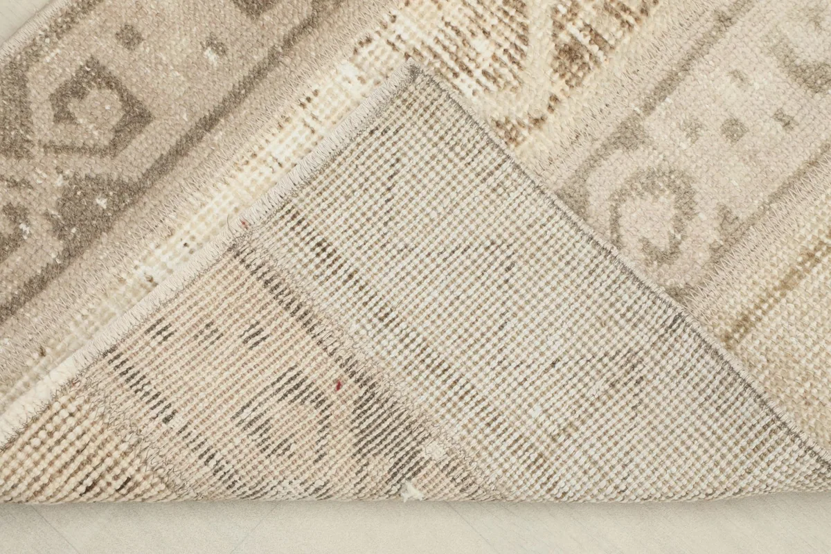 View of the back of the hand-knotted wool pile on cotton foundation, with a corner folded.