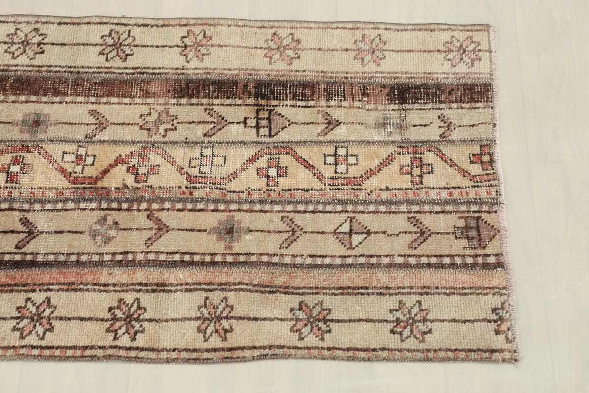 Close-up of the rug's patterns and colors, showing beige, brown, and rust tribal motifs.