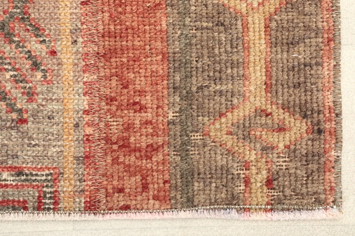 Close-up detail of the rug's edge, showing the hand-knotted wool pile and cotton foundation.