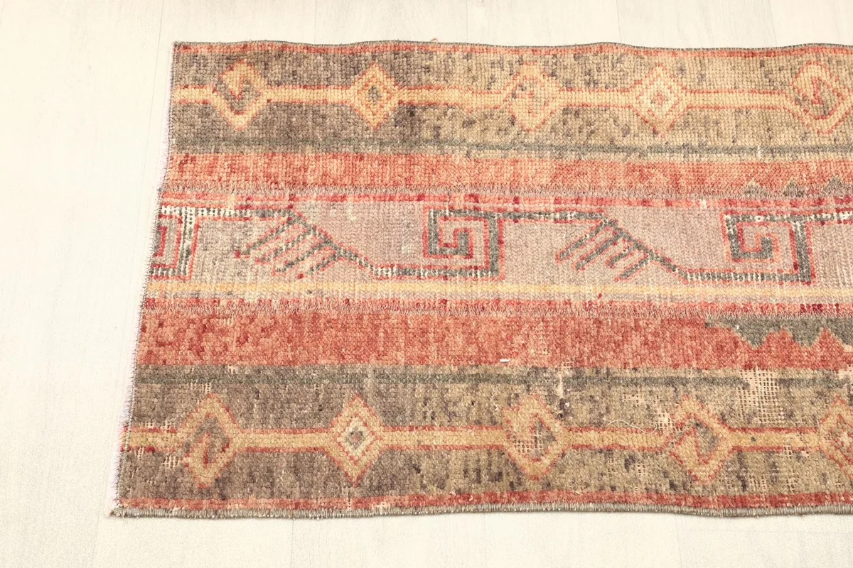 Detailed view of one end of the rug, featuring the distinct striped and geometric patterns.