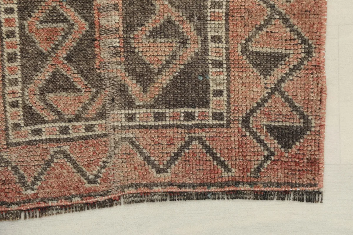 Detail of the rug's end, showing the short fringe and the texture of the wool pile