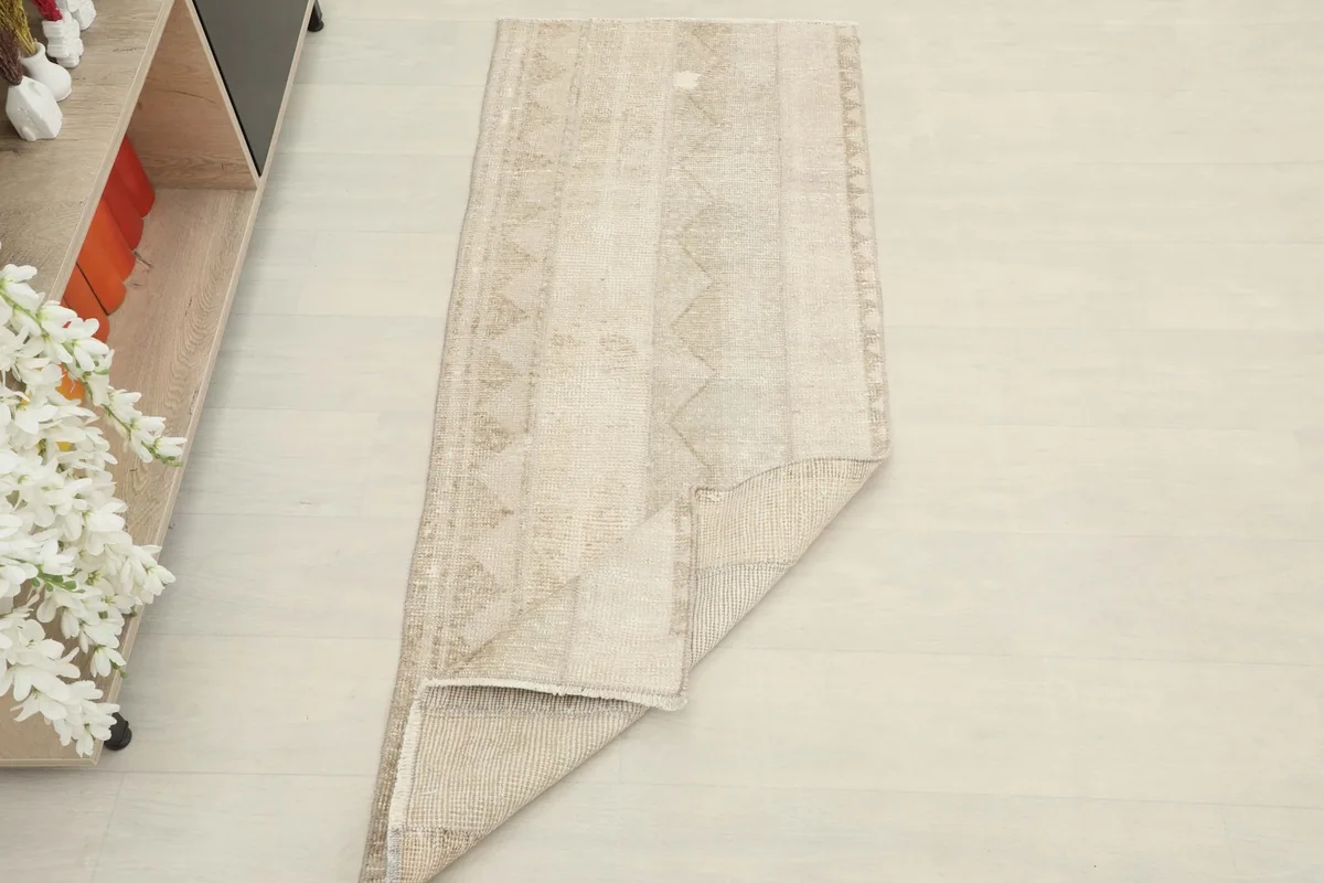 Angled view of the tan runner with a corner folded back, showing its overall shape and texture.