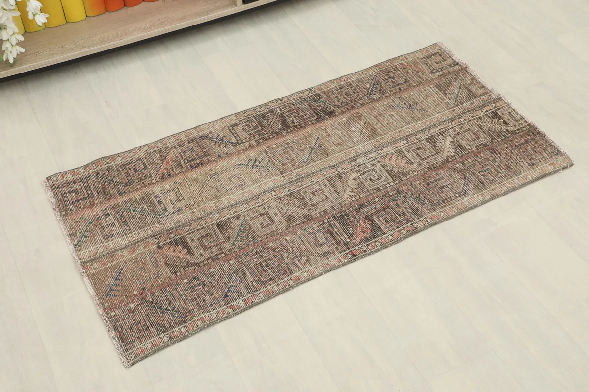 Angled view of the vintage Anatolian rug, highlighting its rich brown and tan geometric patterns.