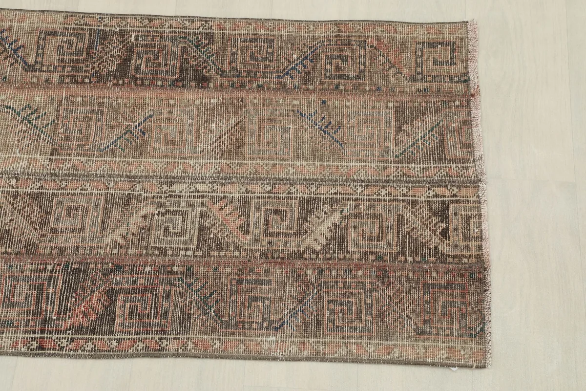 View of one end of the rug, detailing the geometric patterns extending to the fringe.