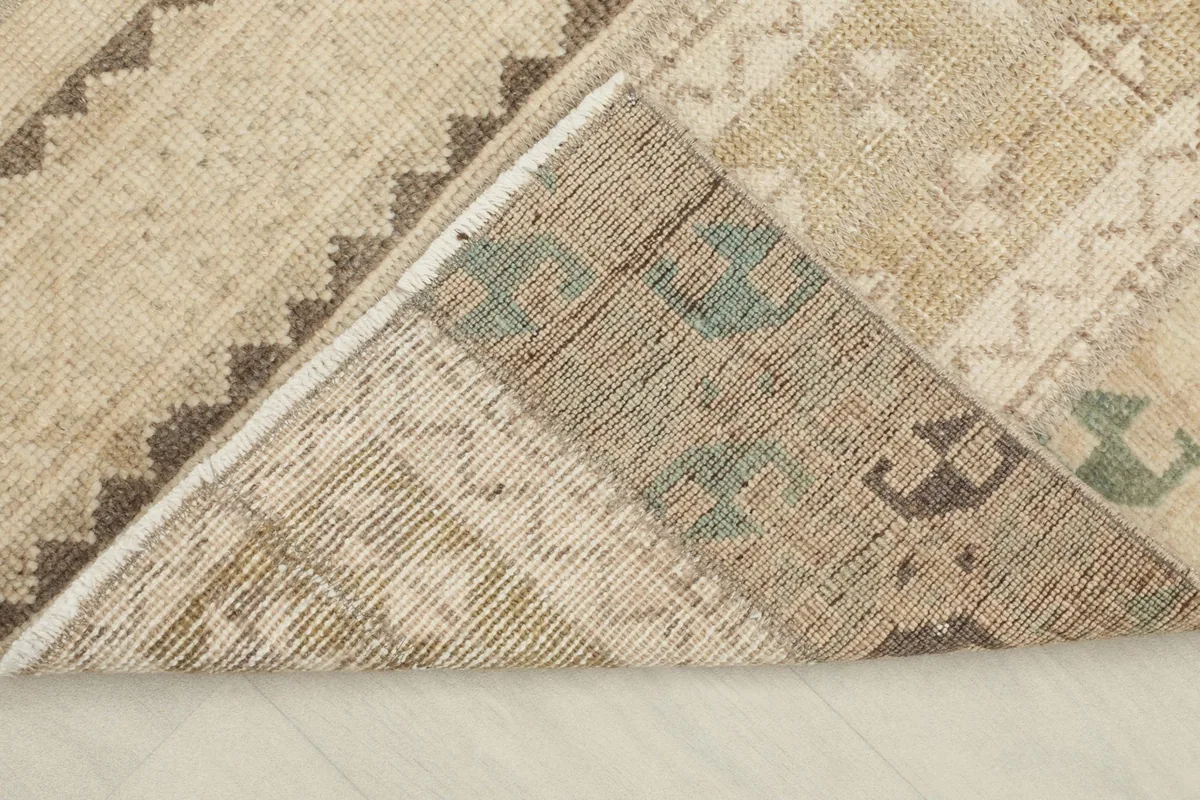 Corner of the rug folded back to reveal the cotton foundation and the reverse side of the knots.