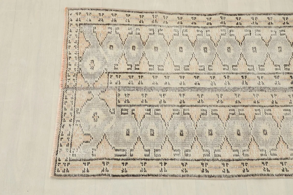 Detail of the rug's bottom border and corner, showing the subtle fringe