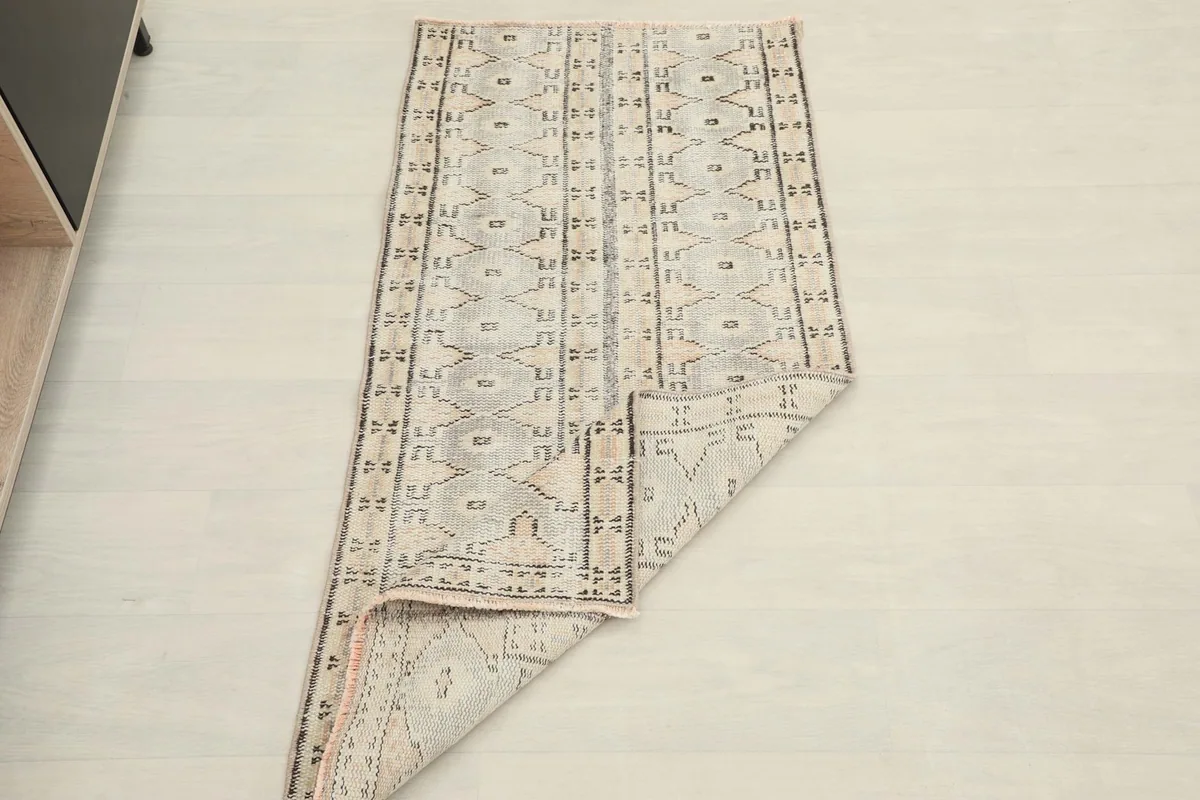 The vintage rug partially folded, showcasing its flexibility and full pattern