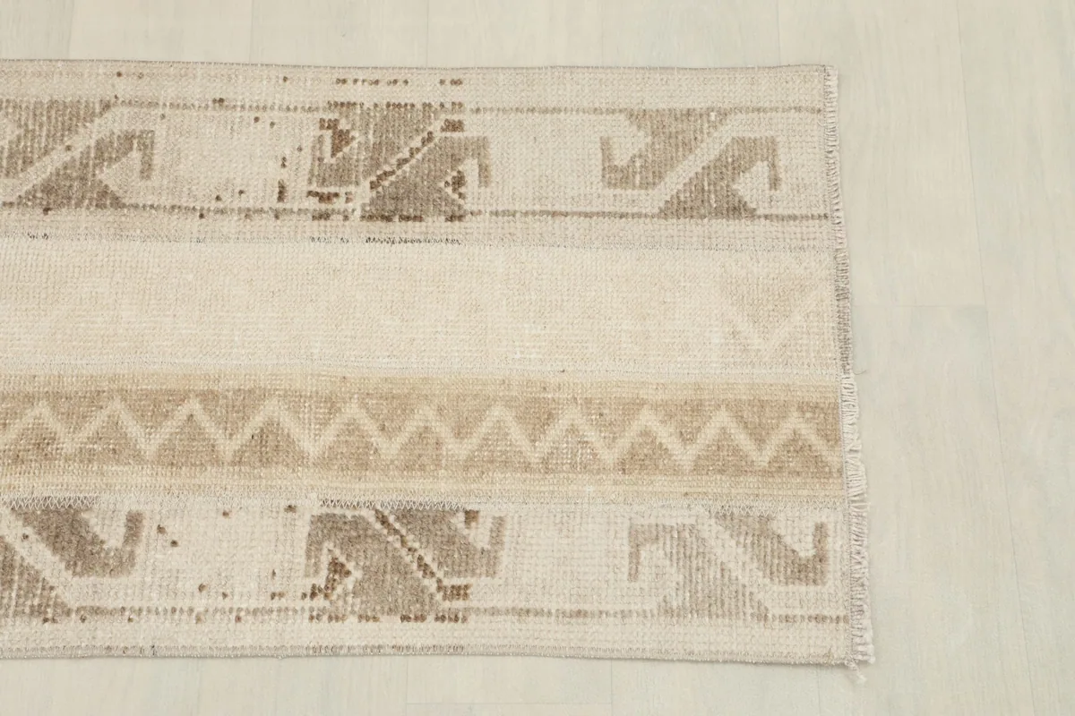 Detailed overhead view of one end of the beige tribal rug, showing pattern variation
