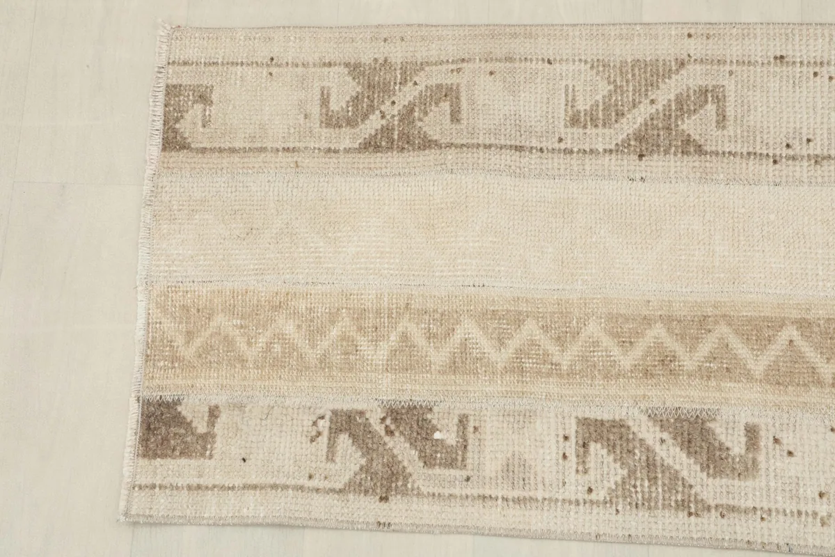 Detailed overhead view of the other end of the beige vintage rug, highlighting motifs