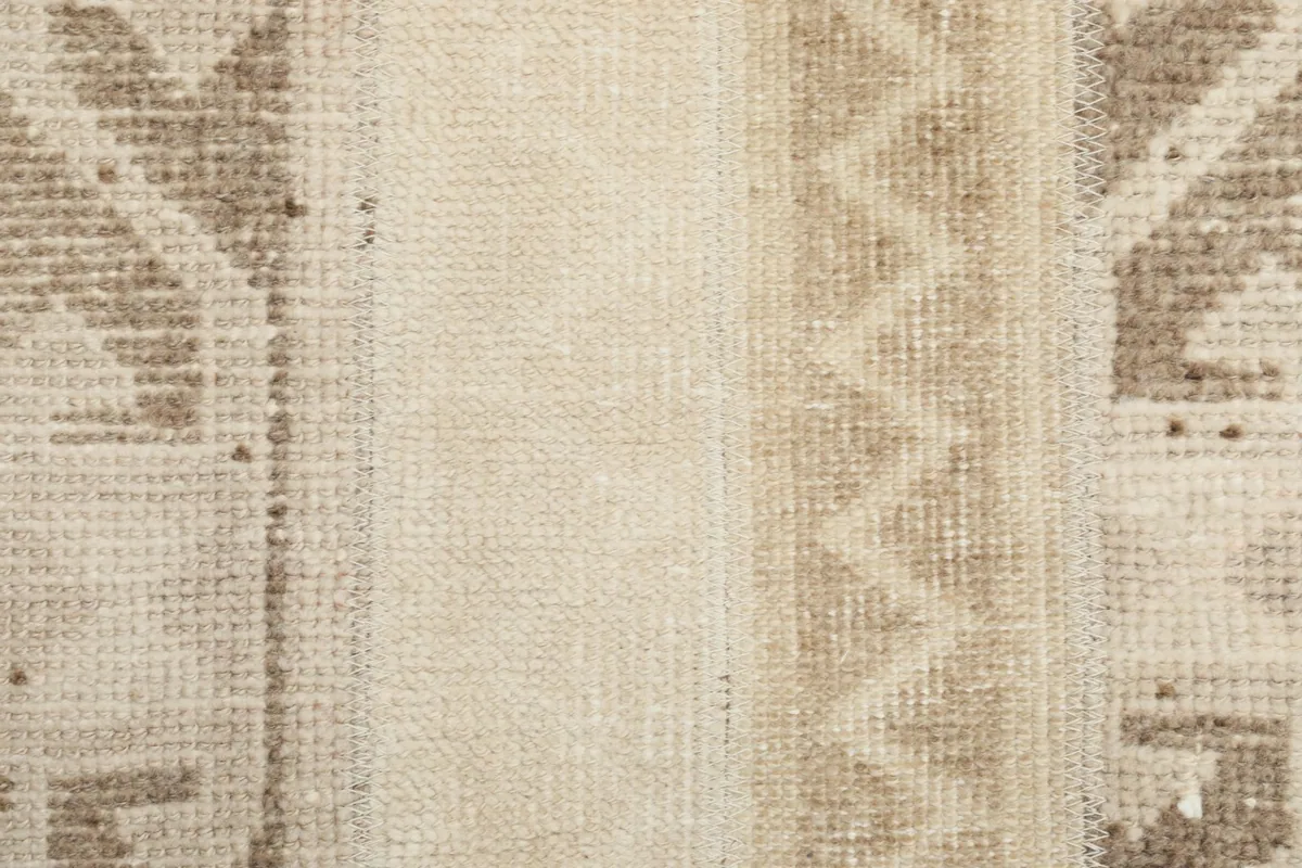 Close-up of the low wool pile and intricate knotting of the beige rug