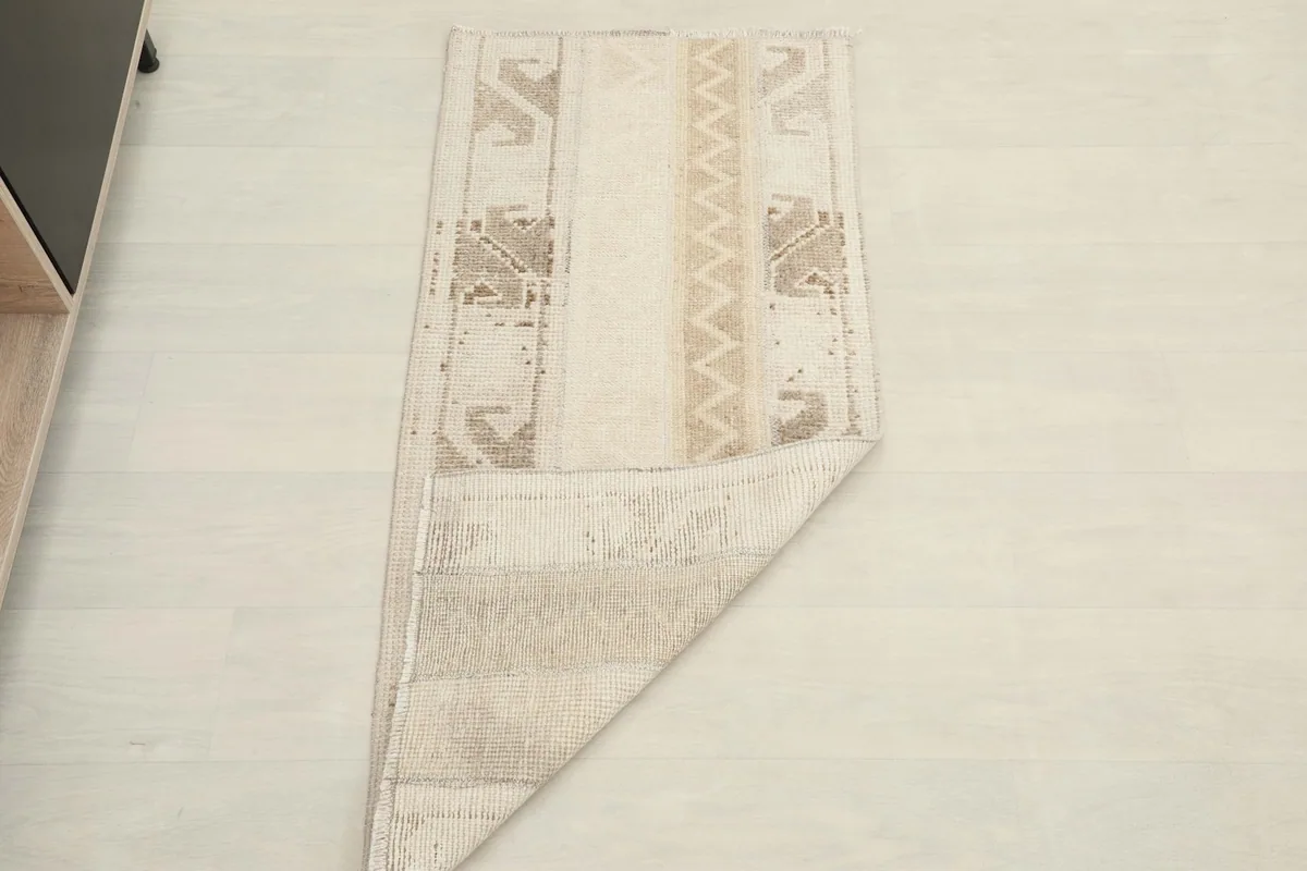 The beige vintage rug partially folded, showing its flexibility and full length