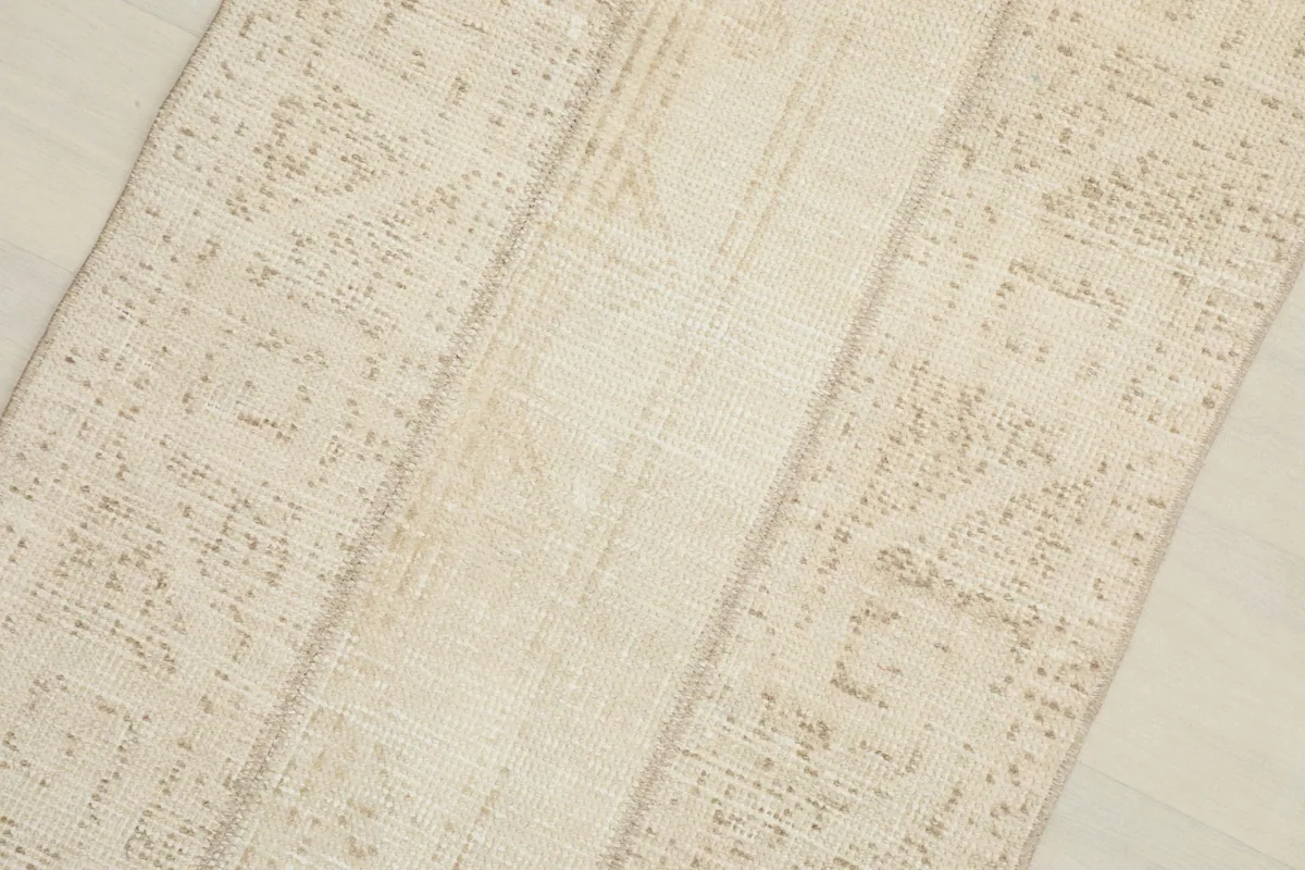 Close-up detail of the rug's surface, highlighting the blend of ivory and tan wool fibers