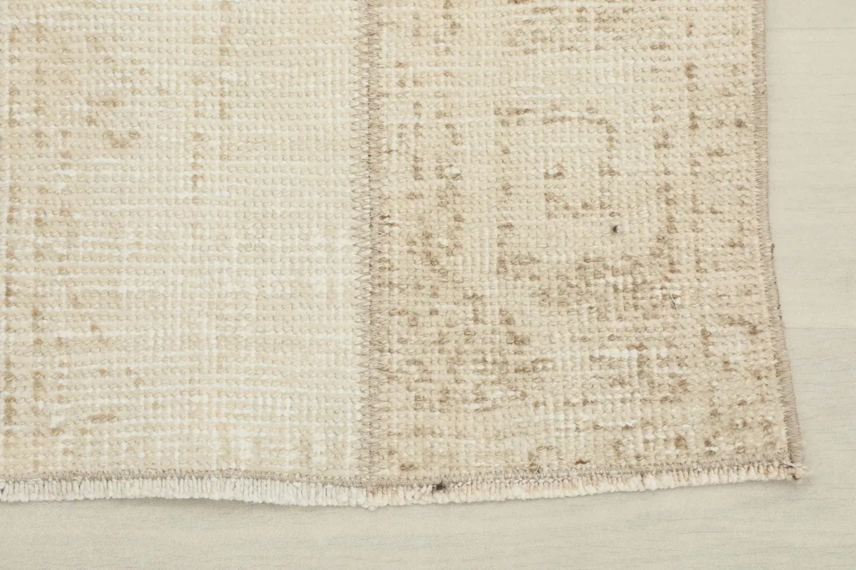 Corner detail of the rug, showing the worn geometric patterns and the edge finish