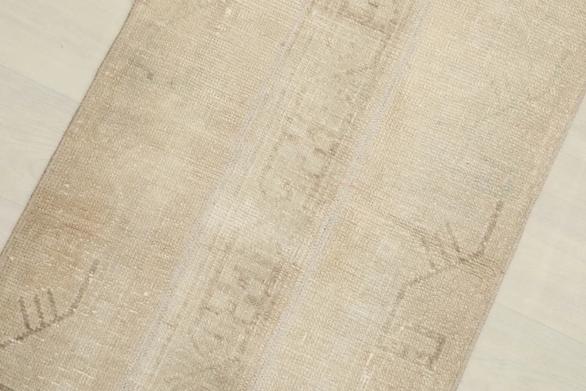 Close-up detail of the rug's surface, highlighting the subtle tan and beige color variations and low pile