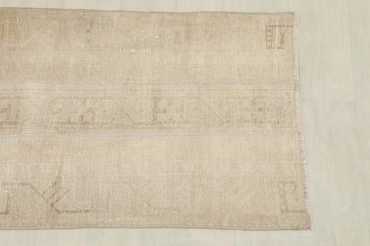 Detail view of one end of the rug, showing the worn texture and faded geometric design elements