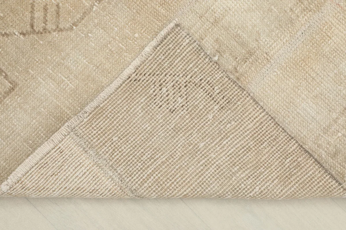 View of the back of the rug, folded to show the cotton foundation and hand-knotted construction