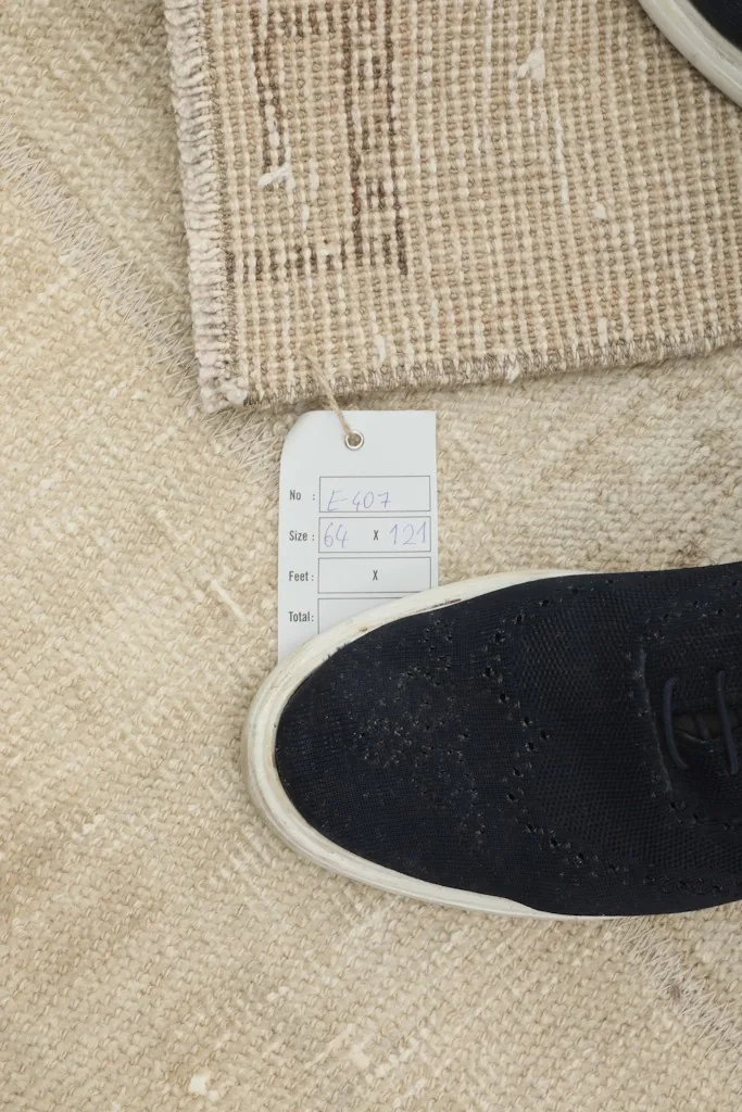 A size tag next to a shoe on the rug, indicating the 2'1" x 4'0" dimensions and scale