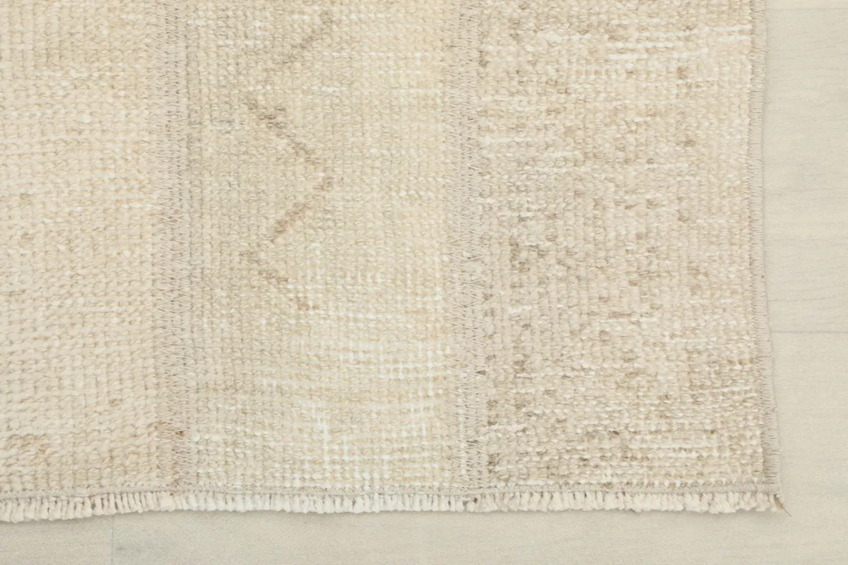 Close-up of the rug's edge and fringe, showing the low pile and vintage wear