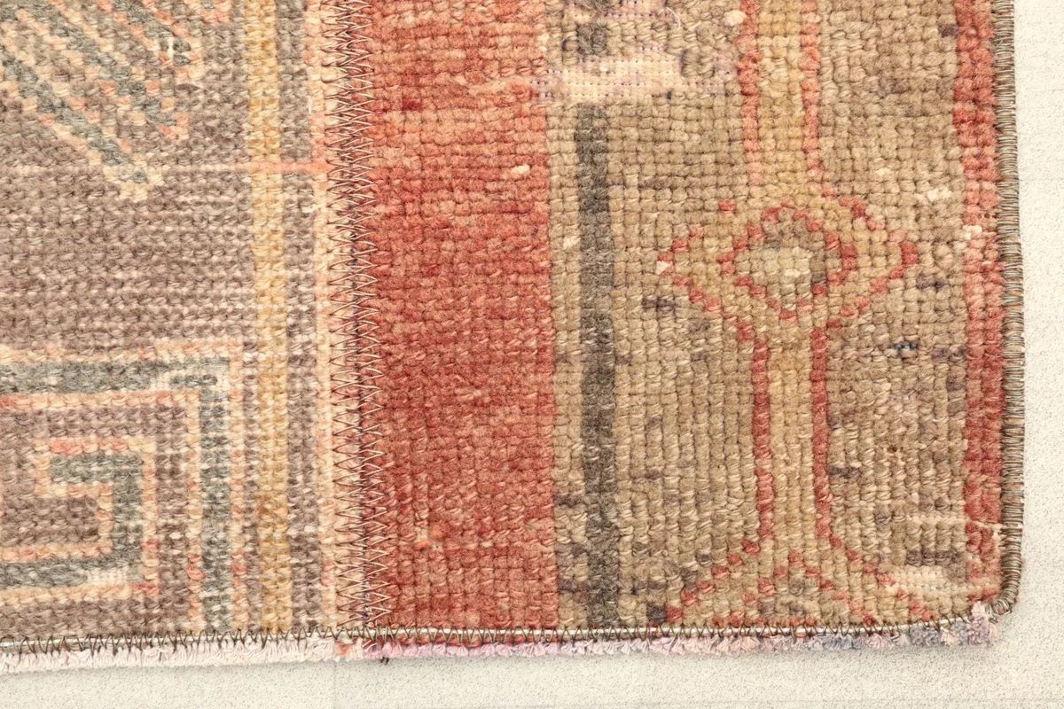 Close-up detail of the hand-knotted wool pile and the distinct rust, beige, and gray color variations.