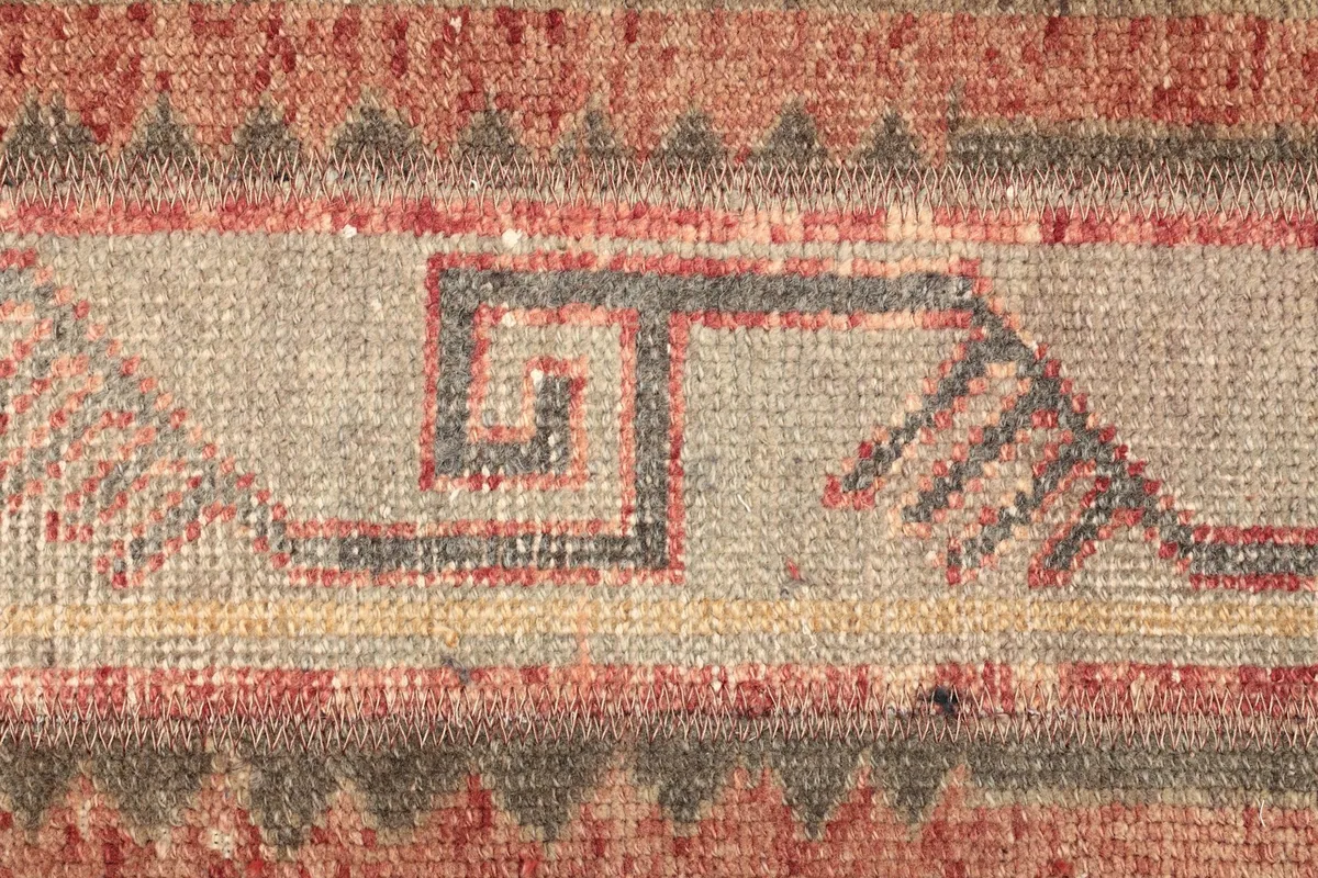 Detailed shot of the central geometric motif in gray and beige, with subtle variations in the pile.