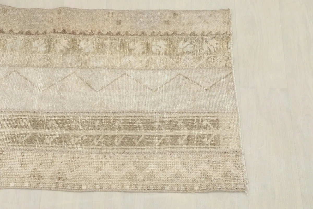 Close-up of the rug's surface, highlighting the geometric patterns and variations in beige tones.