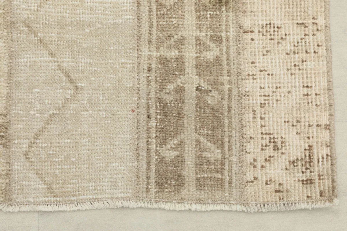 Close-up of one end of the rug, showing the short fringe and the distressed texture.
