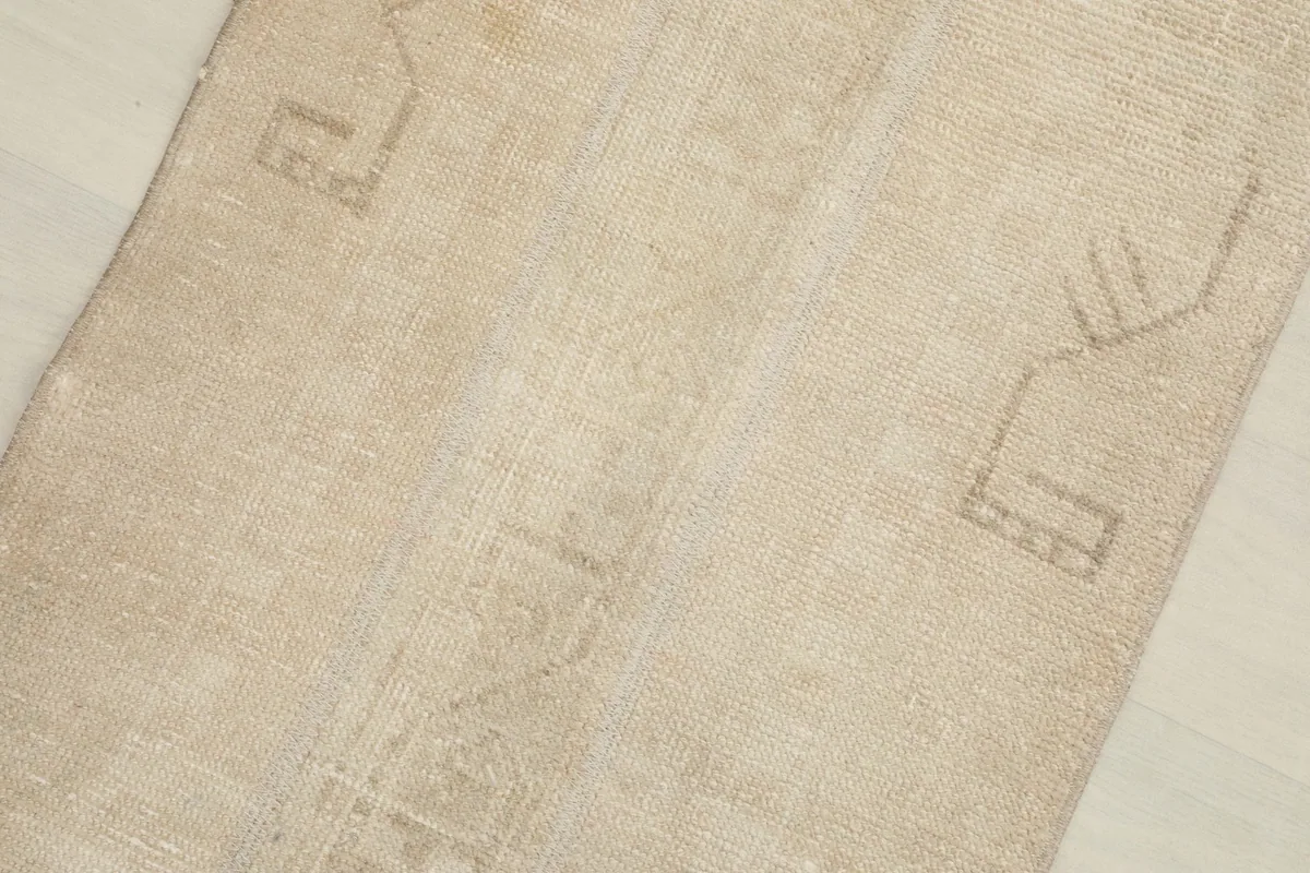 Close-up detail of the rug's surface, highlighting the faint geometric patterns and low pile.