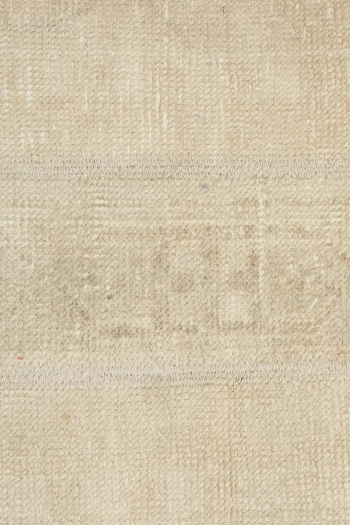 Extreme close-up of the wool pile and weave, showing the texture and muted beige color.