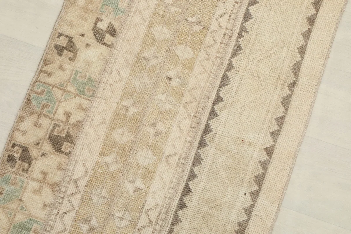 Close-up of the rug's striped pattern showing beige, tan, brown, and green motifs