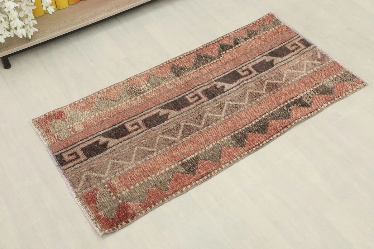 Angled view of the vintage rust, brown, and beige rug, highlighting its tribal design.