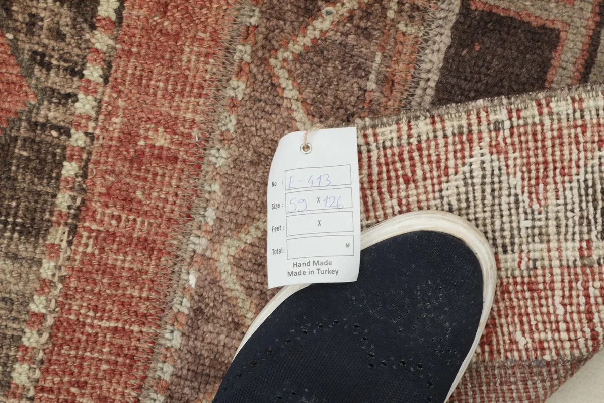 Close-up of the rug's low wool pile texture next to a foot for scale, showing tag.