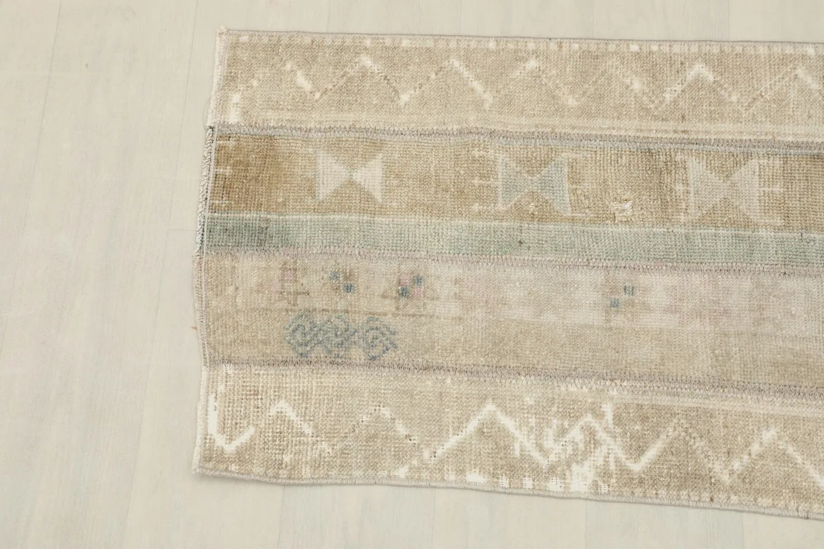 Close-up of the rug's center showing tan, beige, and blue stripes with geometric motifs