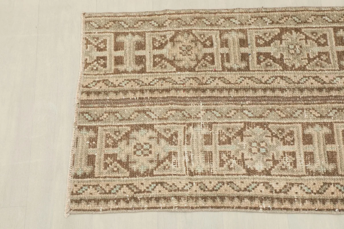 Detail shot of the rug's surface, showing the subtle texture and the distressed appearance of the wool pile.