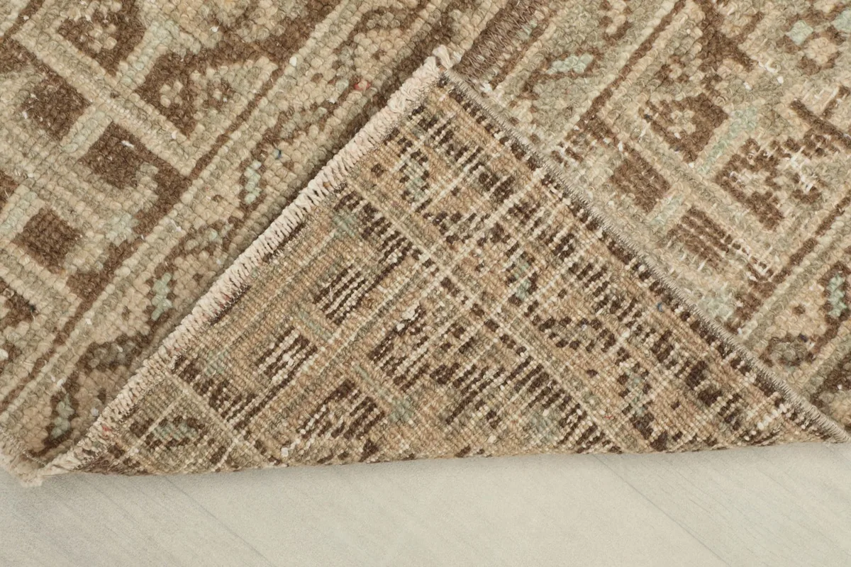 View of the back of the rug, folded to show the hand-knotted foundation and tight weave.