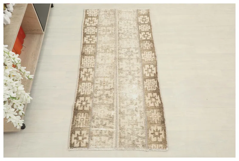 Full top view of the beige and brown vintage Anatolian area rug on a white background.