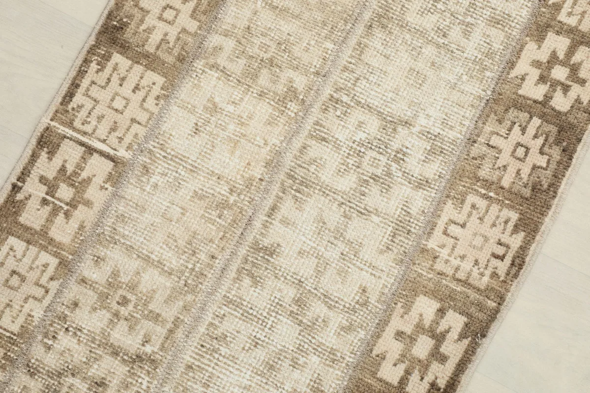 Close-up detail of the rug's central field and tribal geometric motifs in beige and brown.