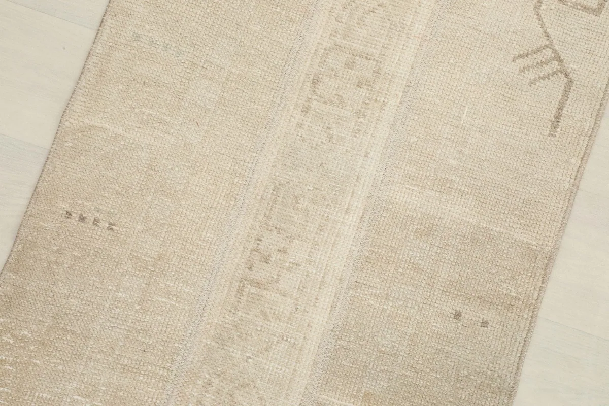 Close-up detail of the rug's central patterned band and subtle variations in beige tones