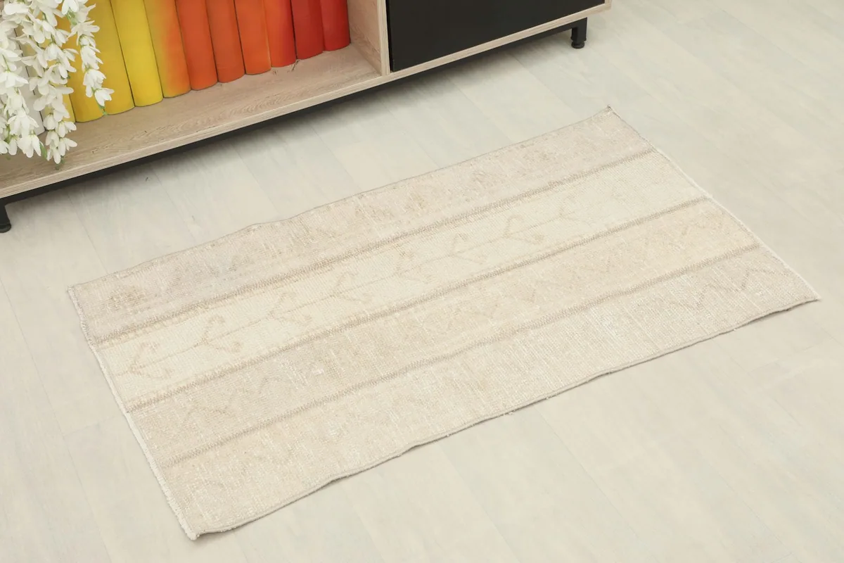 Slightly angled overhead view of the small beige rug, showing its rectangular shape.