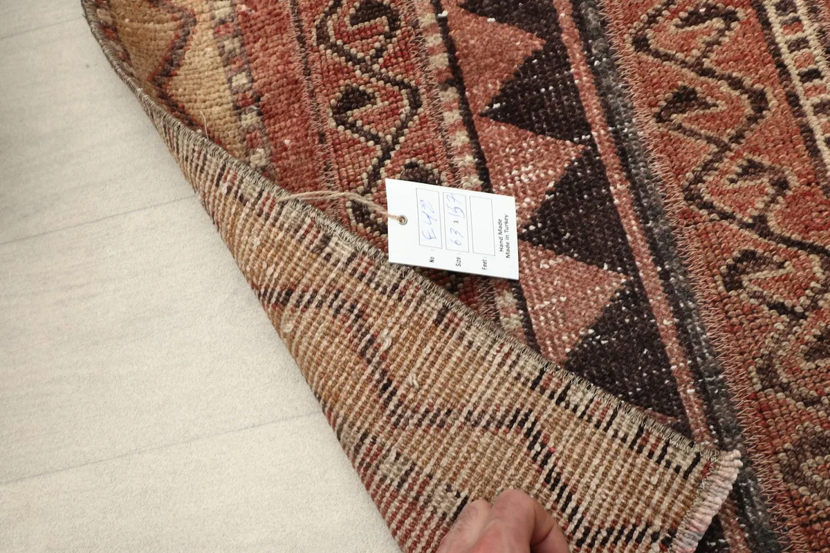 Close-up of the rug's pile and tag, demonstrating the vintage texture and low pile height