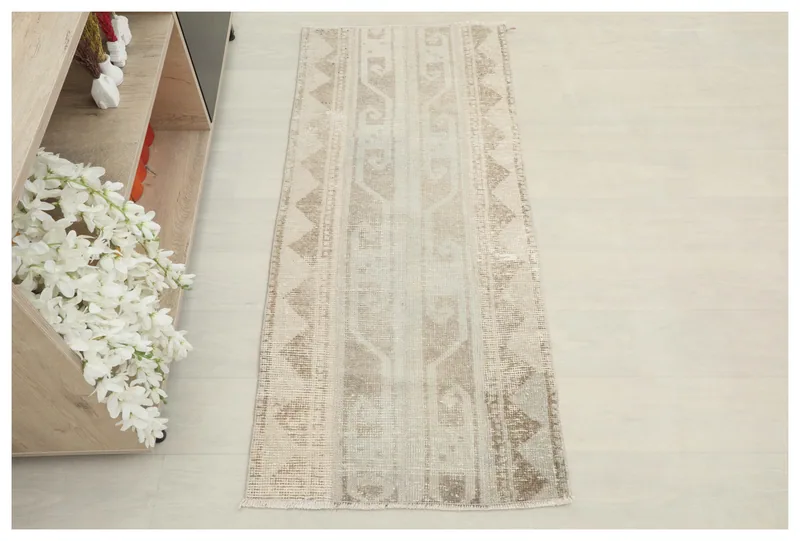 Full top view of the 2x5 beige and tan vintage Anatolian area rug on a white floor.