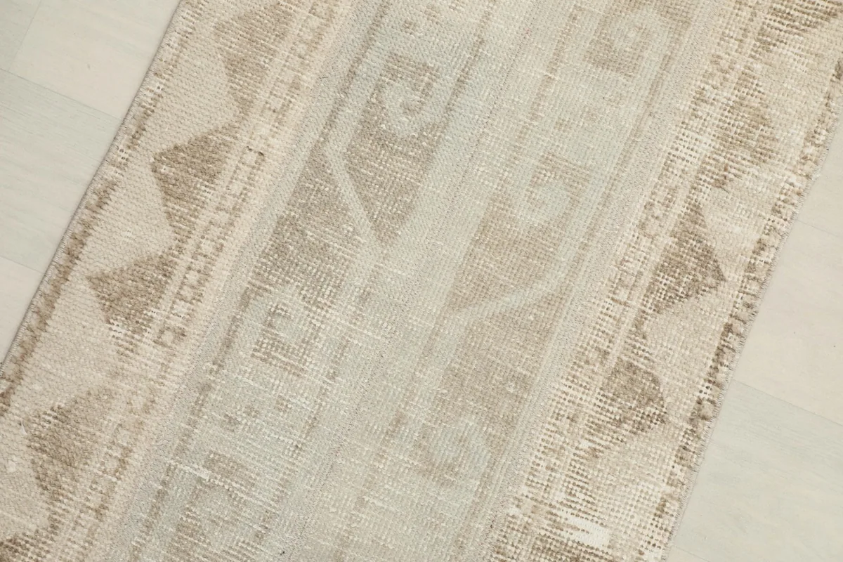 Close-up detail of the hand-knotted pile and geometric patterns in beige and tan.