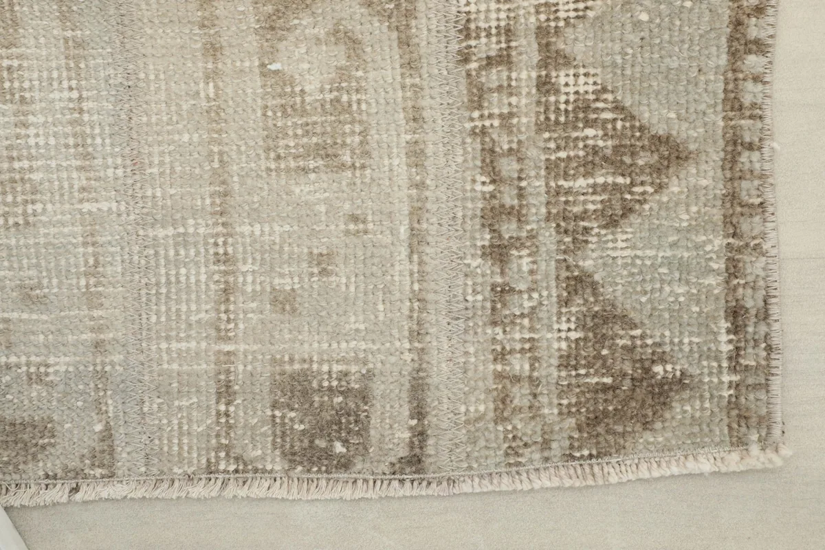 Close-up of the rug's edge, revealing the hand-knotted construction and fringe detail.