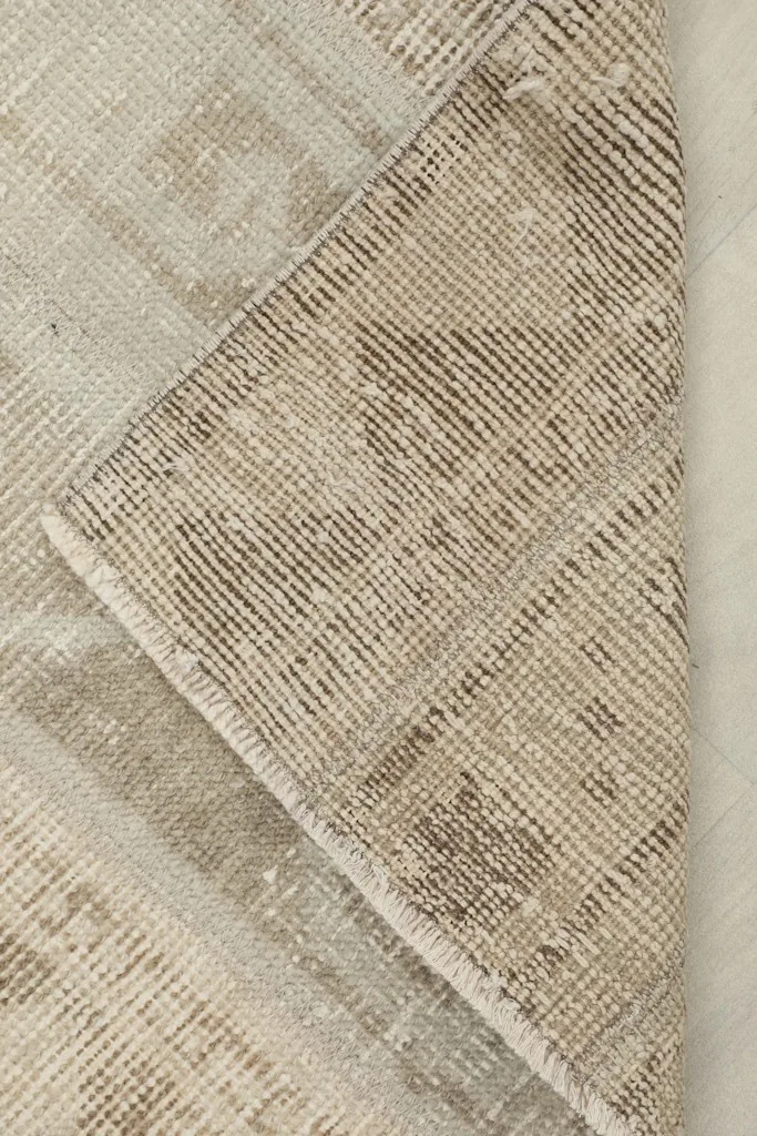 View of the back of the rug, folded to show the cotton foundation and knotting.