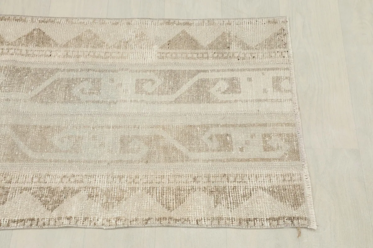 Overhead view focusing on the upper section of the beige and tan rug, highlighting motifs.