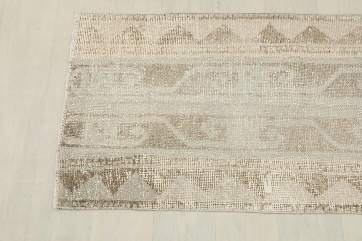 Overhead view focusing on the lower section of the beige and tan rug, showing pattern detail.