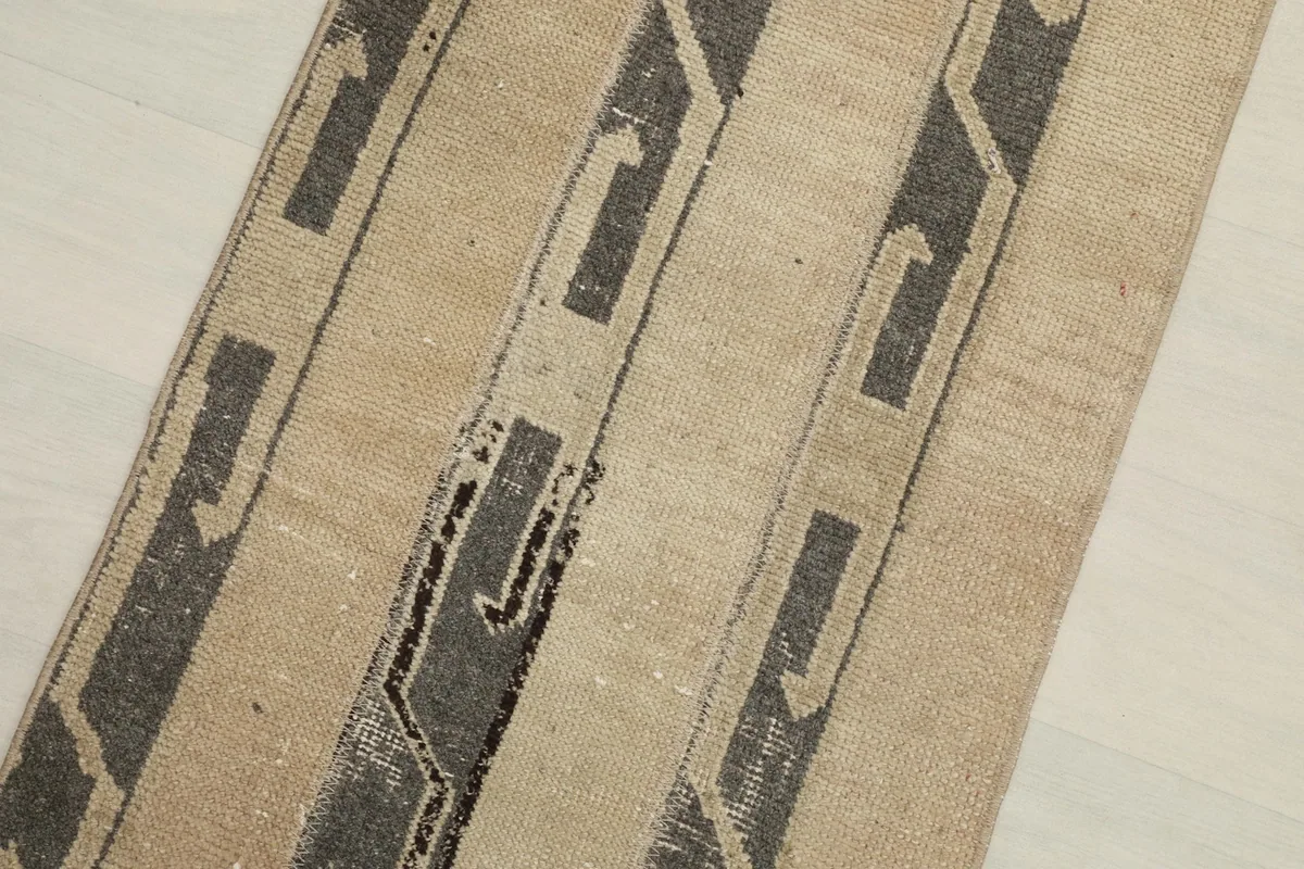 Close-up detail of the abstract gray patterns on the beige field of the runner rug.