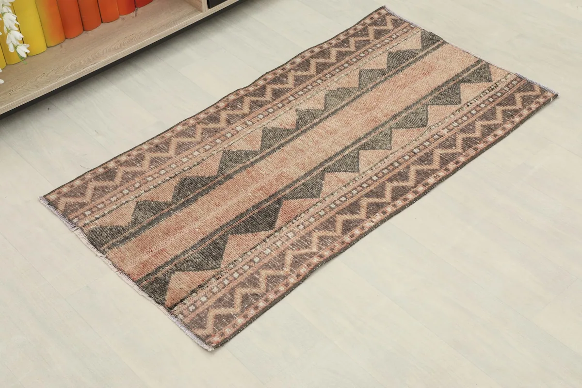 Angled view showcasing the full rust, brown, and black striped geometric pattern of the vintage area rug.