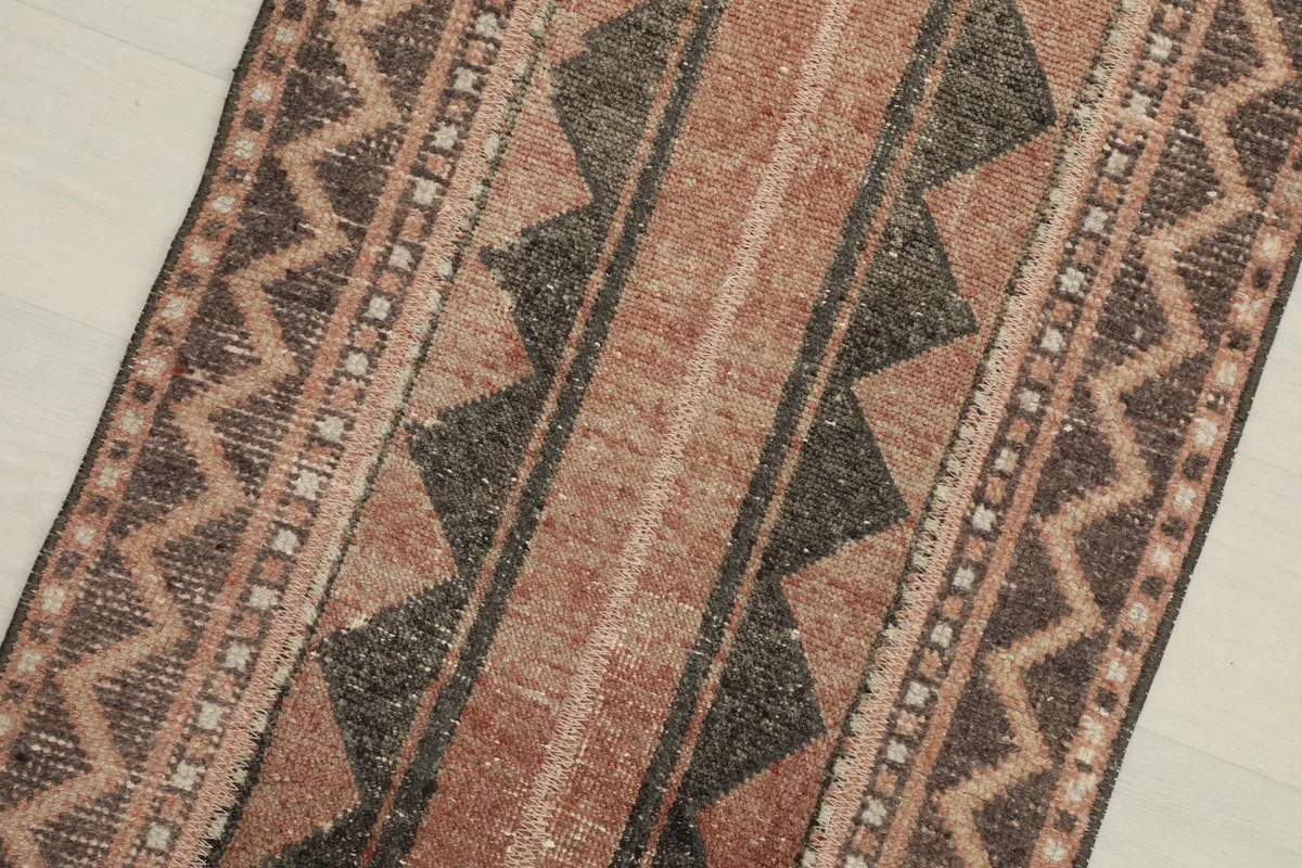 Close-up detail of the central striped and geometric motifs in rust, brown, and black.